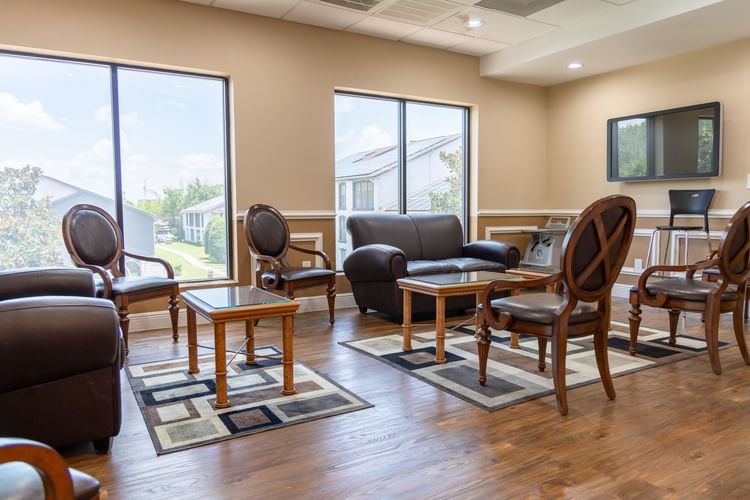 Bright lobby with leather seating, wood tables, and large windows overlooking residential area at Legacy Vacation Resorts