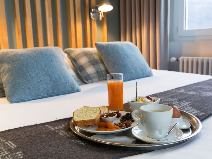 A tray with food kept on a bed at Hotel Beauregard