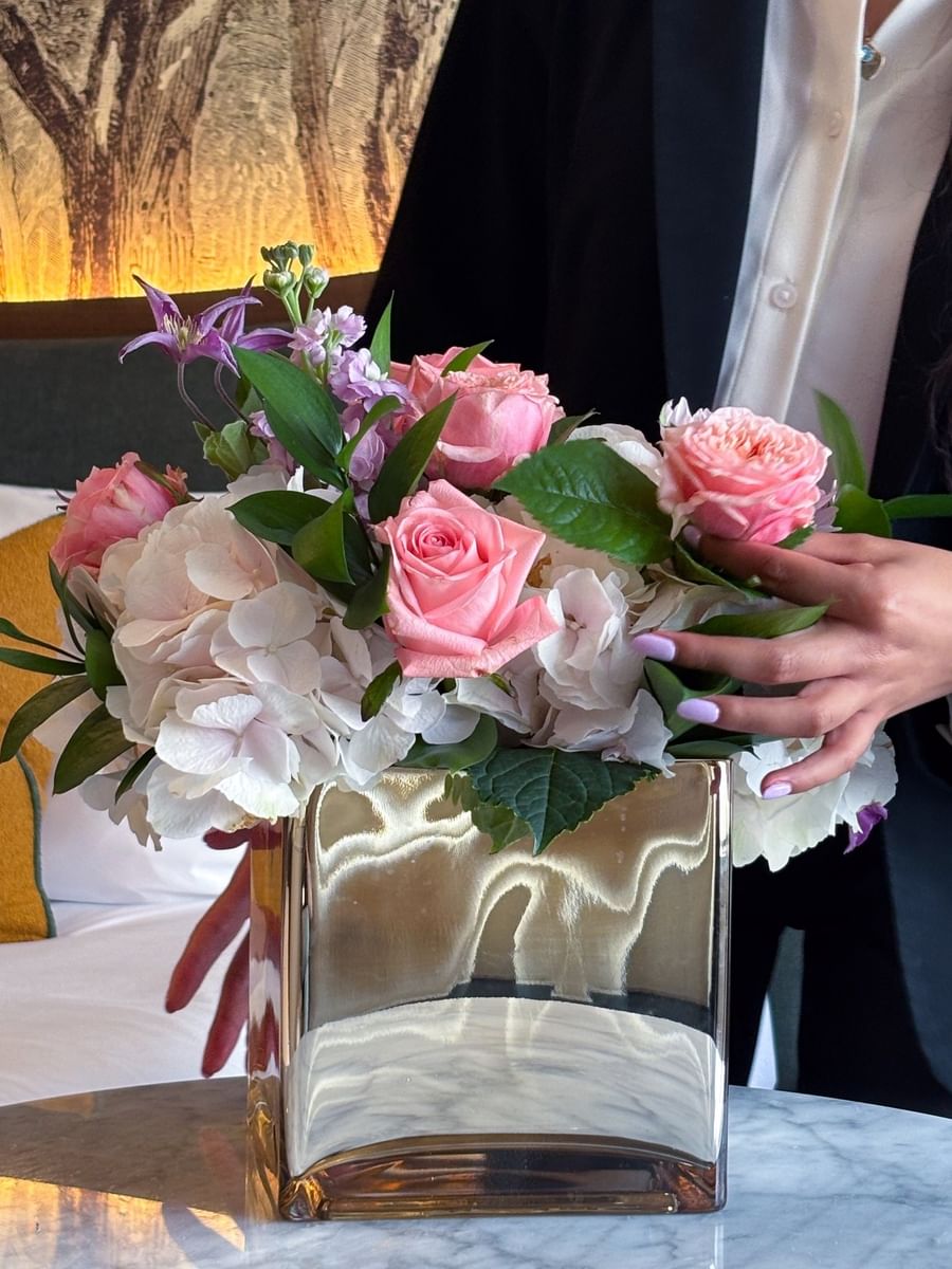 Bouquet of roses and hydrangeas in a gold vase held by a guest at The Capital Hotel, Apartments and Townhouse