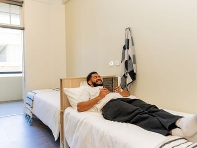 Student reading a book in Twin Room at UniLodge Herston.