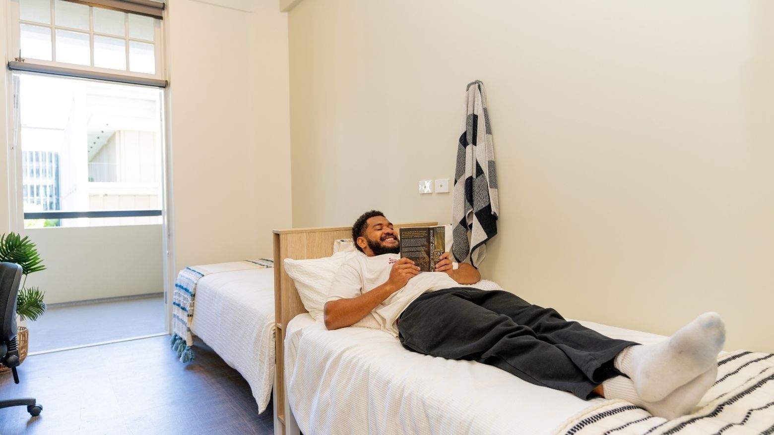 Student reading a book in Twin Room at UniLodge Herston.