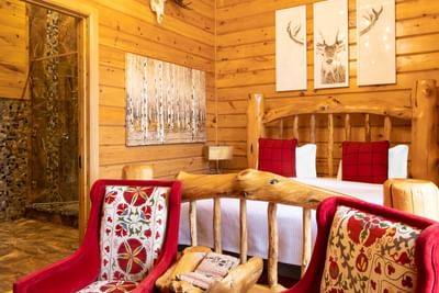 King bed, wooden interior & red comfy wing chairs in King Executive Log Cabin at Retro Suites Hotel