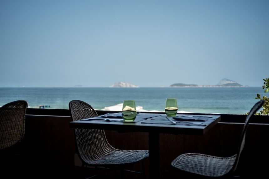 Outdoor dining table arranged by the ocean at Janeiro Hotel