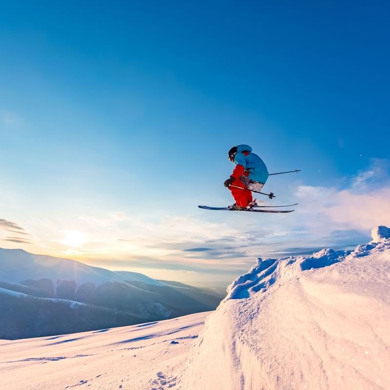 Skier soaring through a snowy slope on skis near Blackcomb Springs Suites