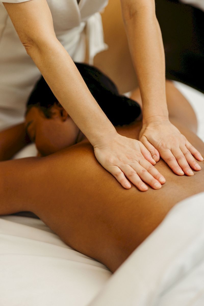 Masseuse hands giving relaxing back massage to woman lying on a plush treatment table at Guerlain Spa at Hotel X Toronto