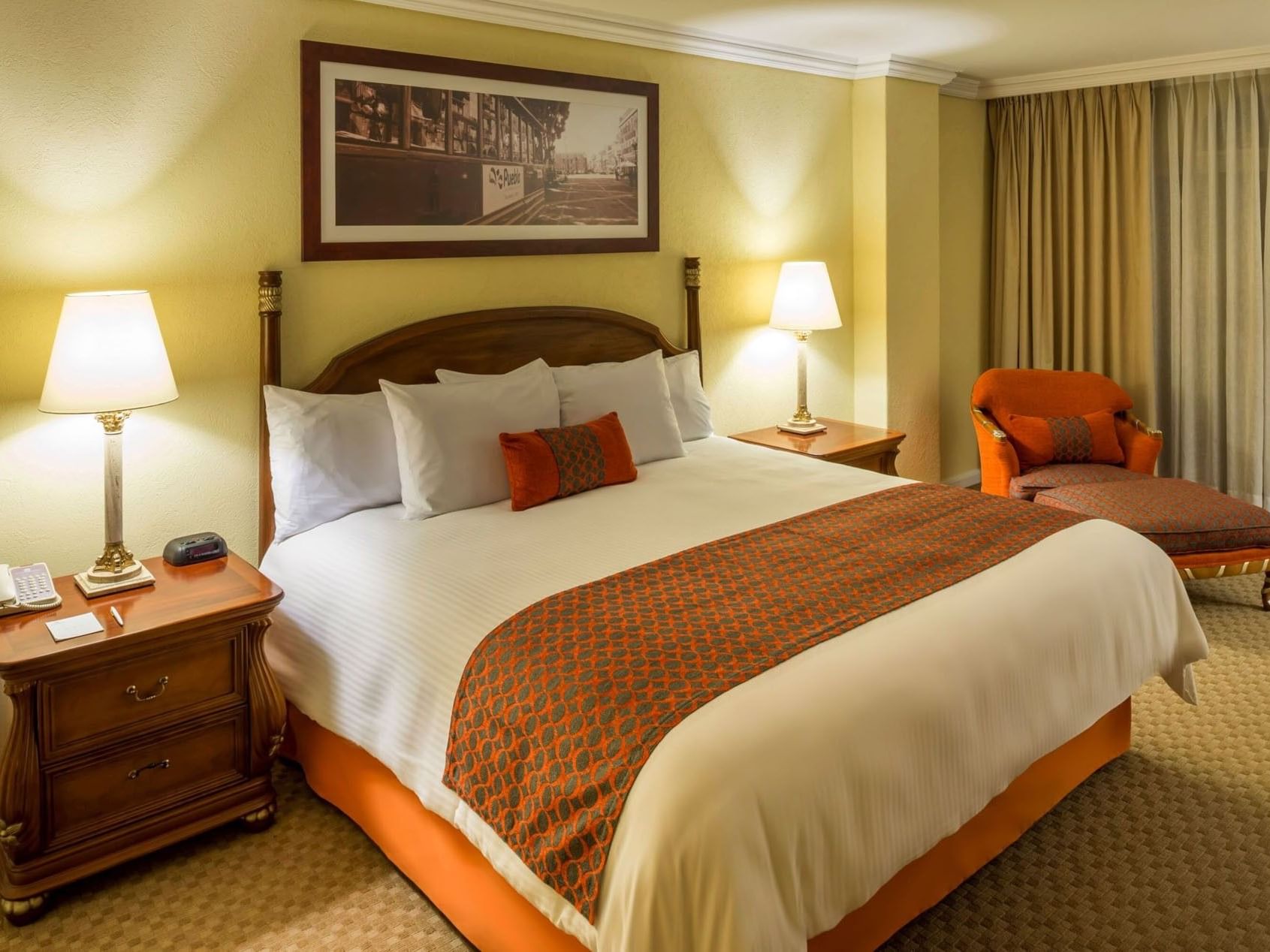 King Presidential Suite with classic furniture, warm lamps, and an orange armchair at Camino Real Puebla Angelopolis
