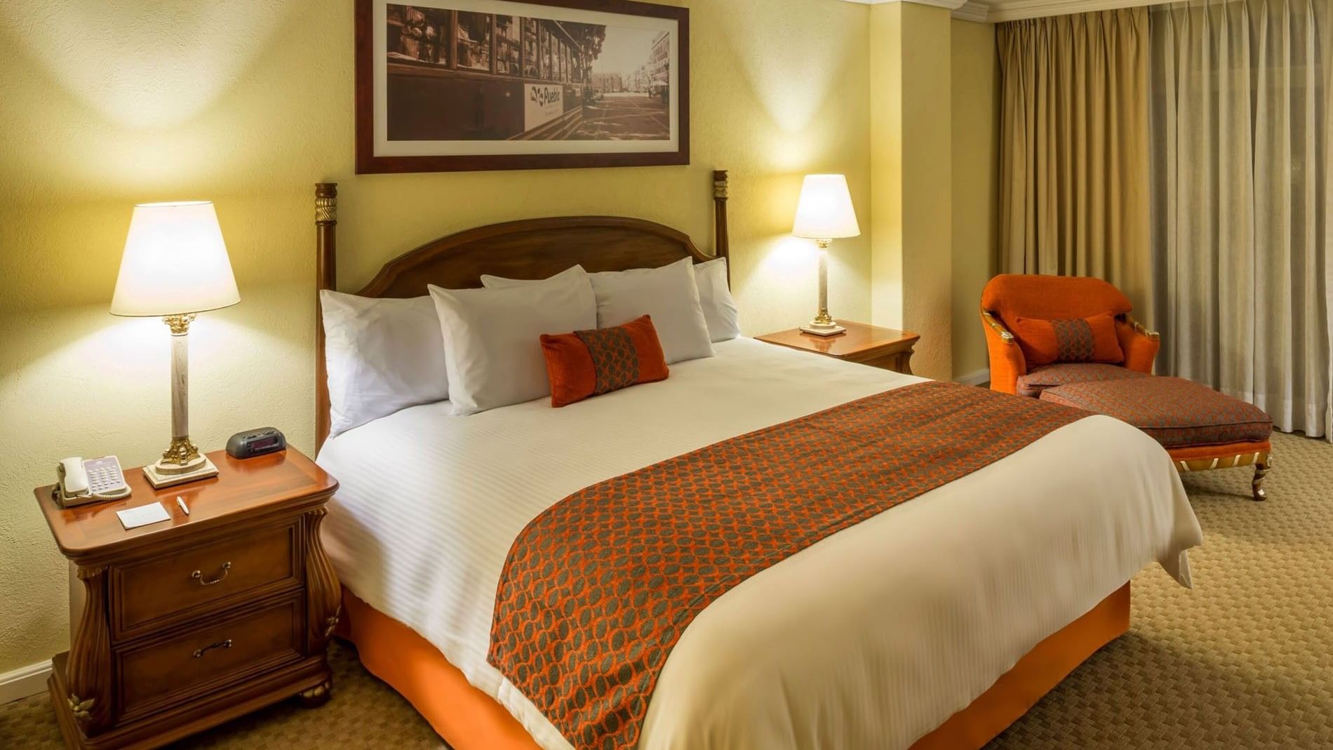 King Presidential Suite with classic furniture, warm lamps, and an orange armchair at Camino Real Puebla Angelopolis