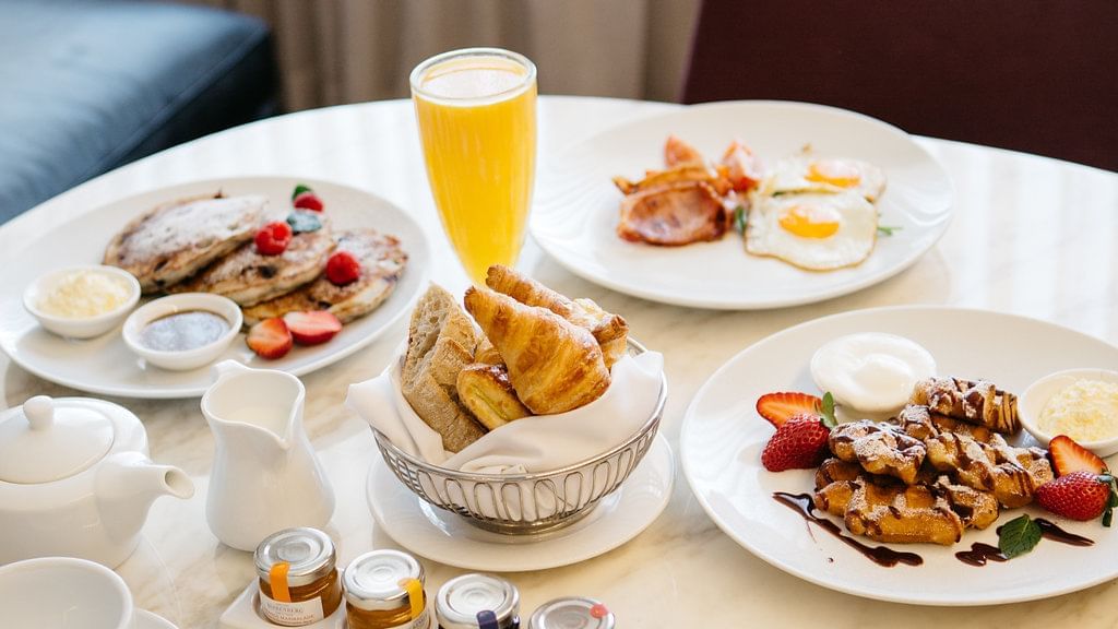 Breakfast spread on a table with pancakes, pastries and juice In Room Dining at Sofitel Brisbane Central