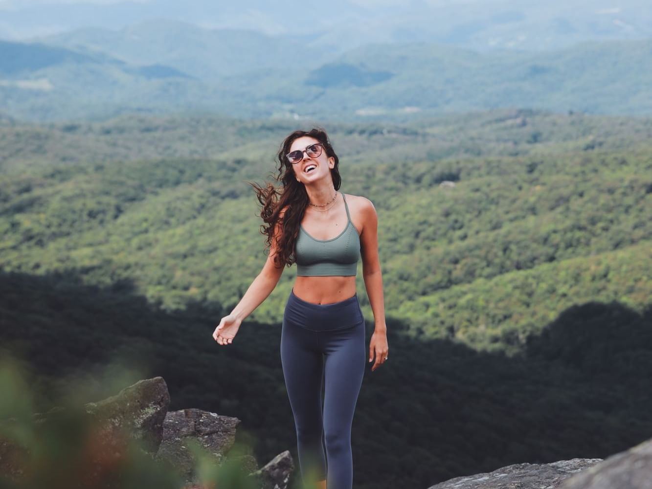 A woman enjoying wind on top of Grandfather Mountain near The Embers Hotel