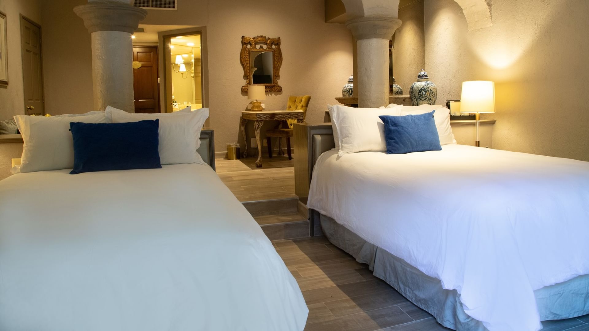 Master Suite con dos camas dobles, decoración colonial y baño visible al fondo en Quinta Real Guadalajara