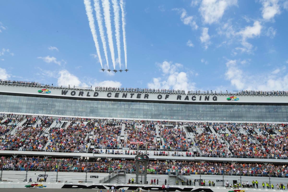A large crowd watches an air show at Daytona International Speedway.