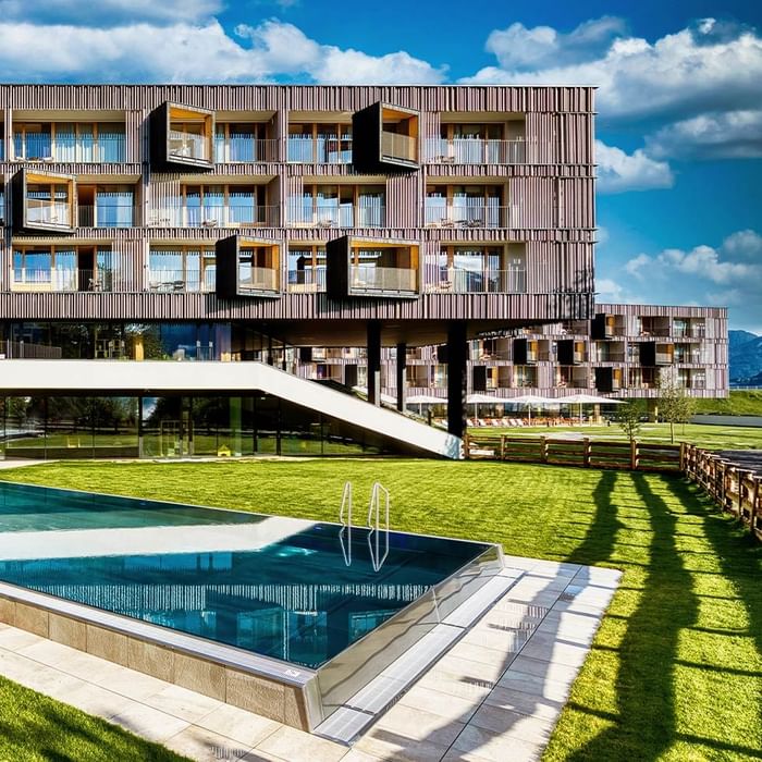 Piscina di design vicino a un moderno edificio residenziale con giardino e balconi.