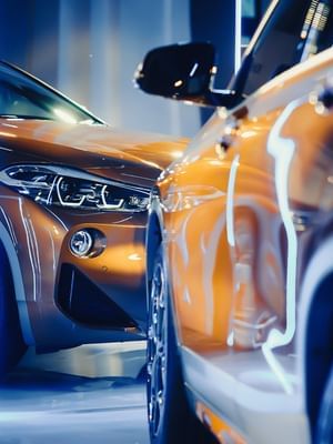 Close-up of two cars in the parking lot with bright lights reflecting off their surfaces at Warwick Reine Astrid - Lyon