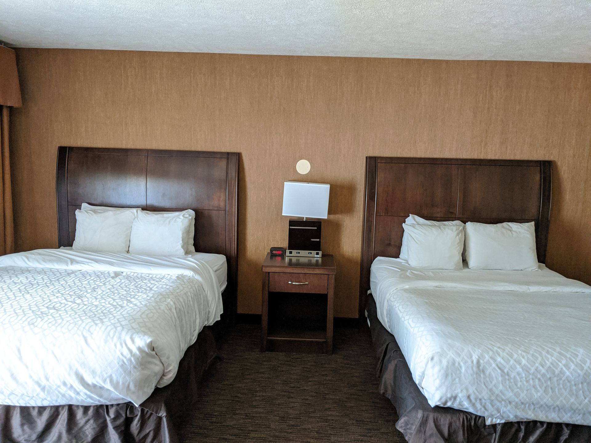 Two queen beds with white linens and pillows in a room at Evergreen Resort in Cadillac.