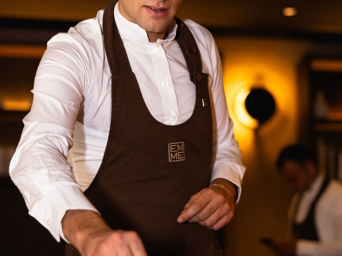 A chef in a white shirt and brown apron cooking in a kitchen at Margutta 19