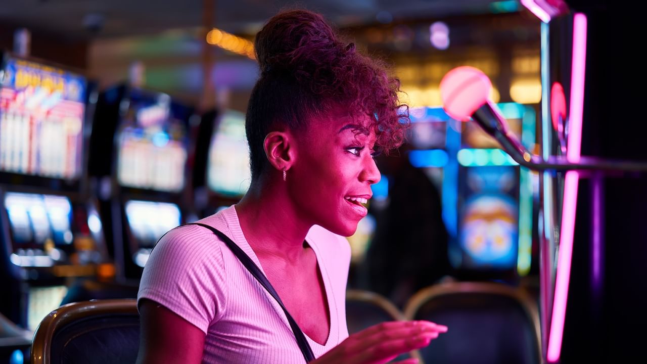 Woman smiling at a slot machine in a casino.