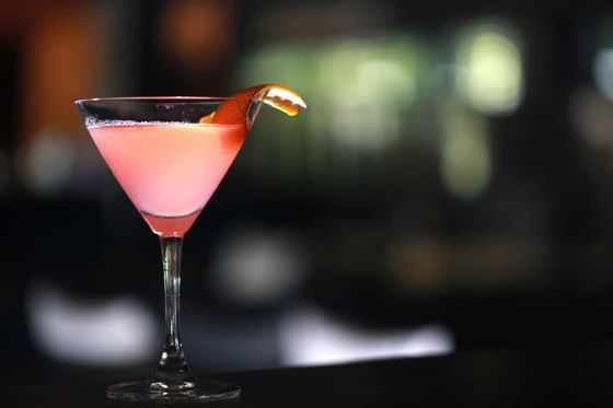Pink cocktail with orange garnish in a martini glass at Peppers Seminyak