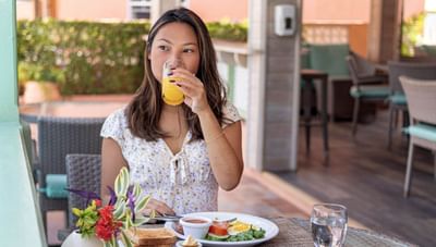 Woman drinking a glass of orange juice over a plate of fried eggs and healthy vegetables at Worthing Court Apartment