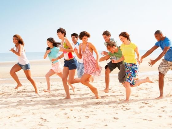 A group of people running on the beach while smiling near the beach at Plaza Pelicanos Club Beach Resort