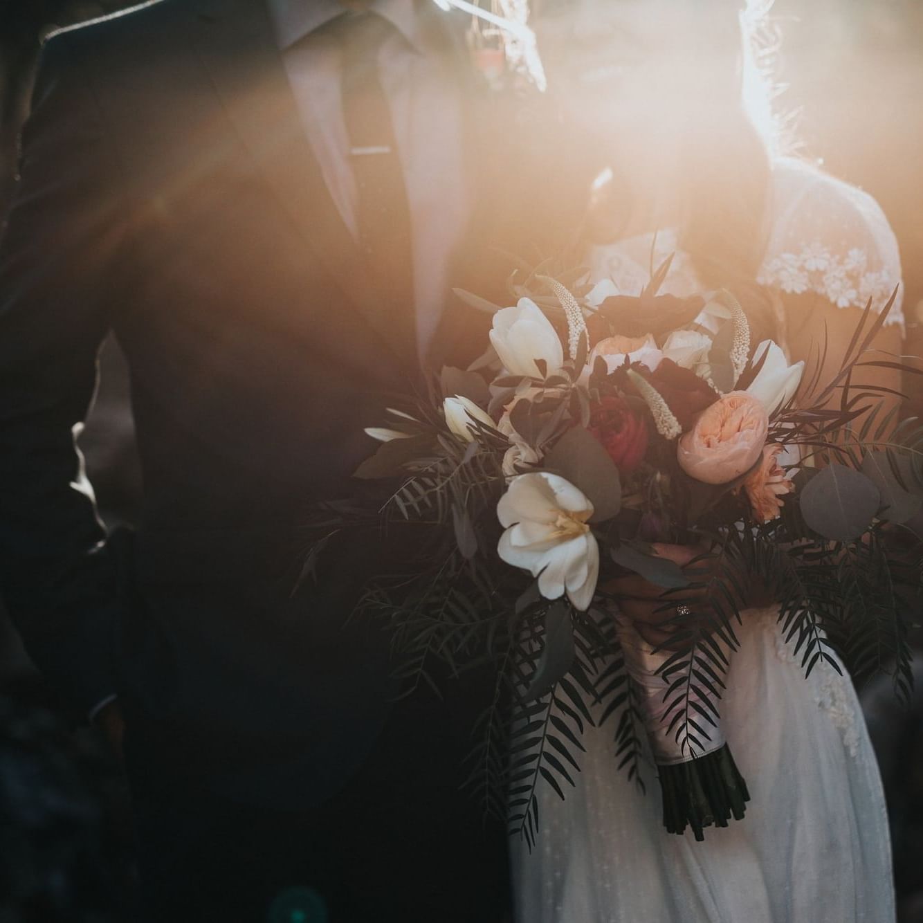 Bride and groom with sun behind them.