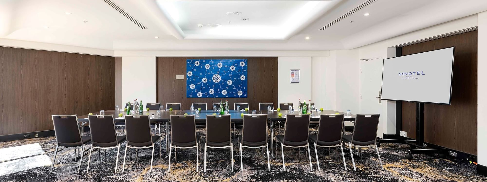 Boardroom set-up facing the projector screen in The Yarra Room at Novotel Sydney on Darling Harbour