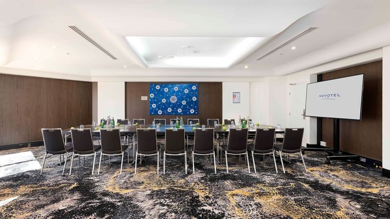 Boardroom set-up facing the projector screen in The Yarra Room at Novotel Sydney on Darling Harbour