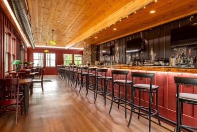 The Brown Swan with stools, tables, and bar counter in The Lodge at Schroon Lake