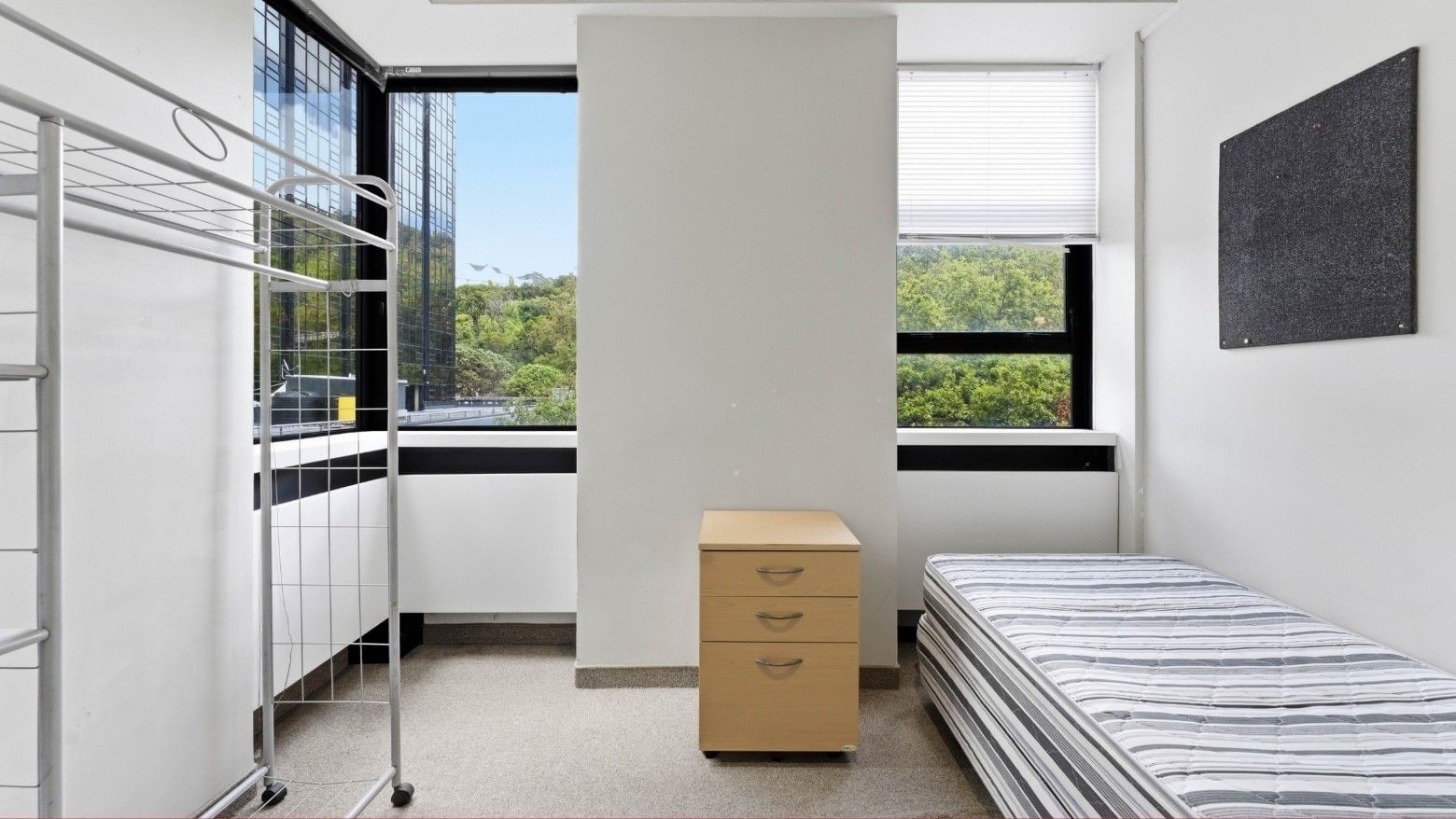 Interior of a modern room with a bed, desk, and windows at UniLodge Stafford House.