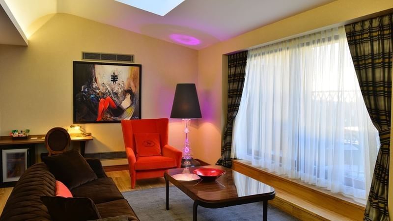 Brown sofa by a red armchair surrounding a coffee table in Ankara Suite with Terrace at Warwick Ankara