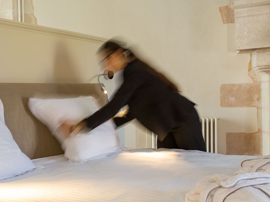 A maid preparing a bed in a room at Chateau de Dissay