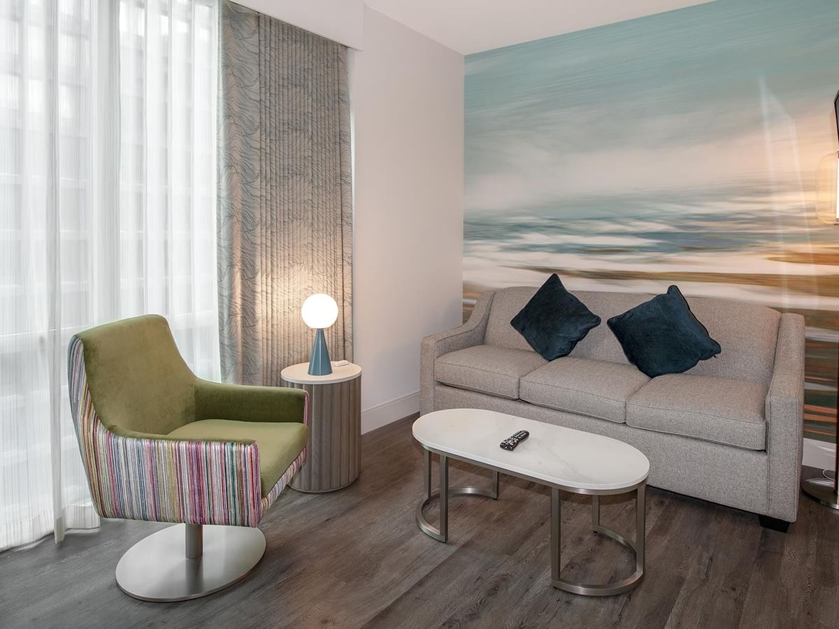Living area of a hotel room with sofa, chair, and coffee table.