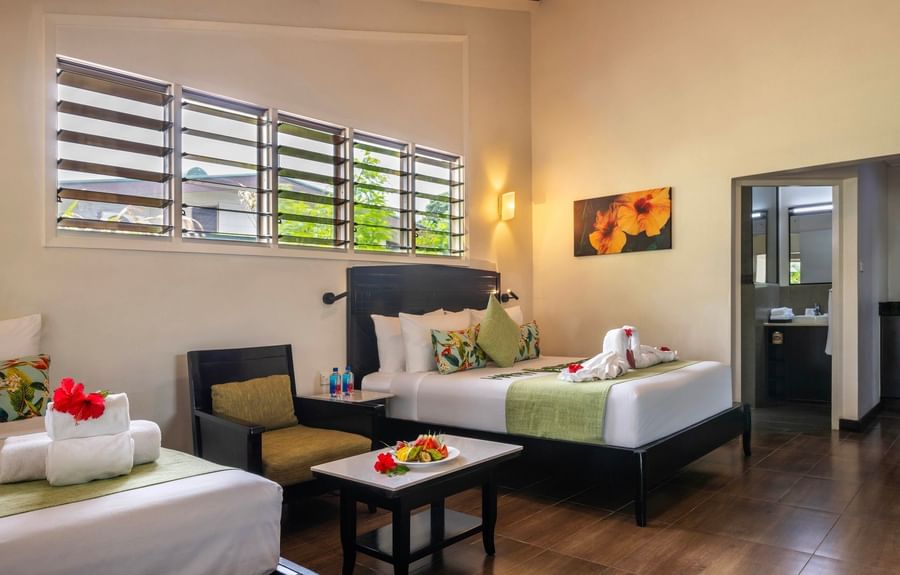 Two beds with tropical decor and fruit plate on a table at Tokatoka Resort Fiji International Airport.