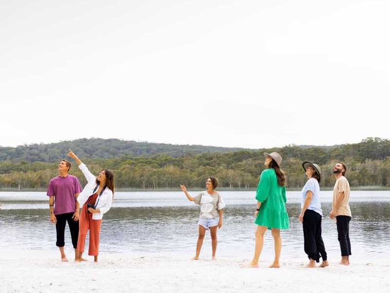 A group of people standing on a beach next to a lake near Sofitel Brisbane Central