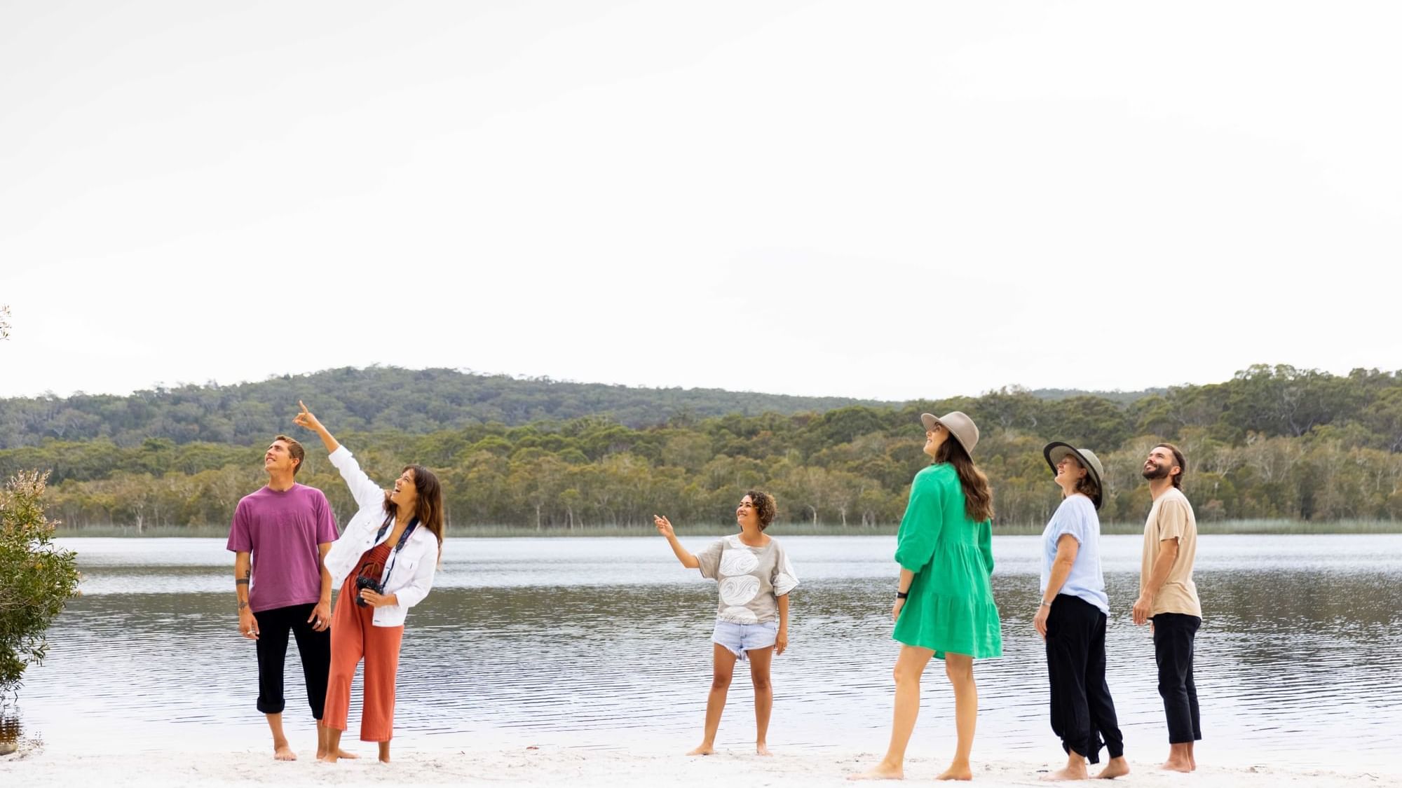 A group of people standing on a beach next to a lake near Sofitel Brisbane Central