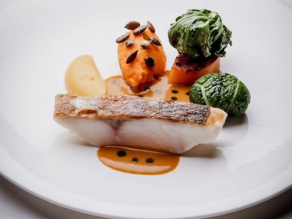 Plate with fish, vegetables, and sauce at The Capital Hotel, Apartments & Townhouse - London.
