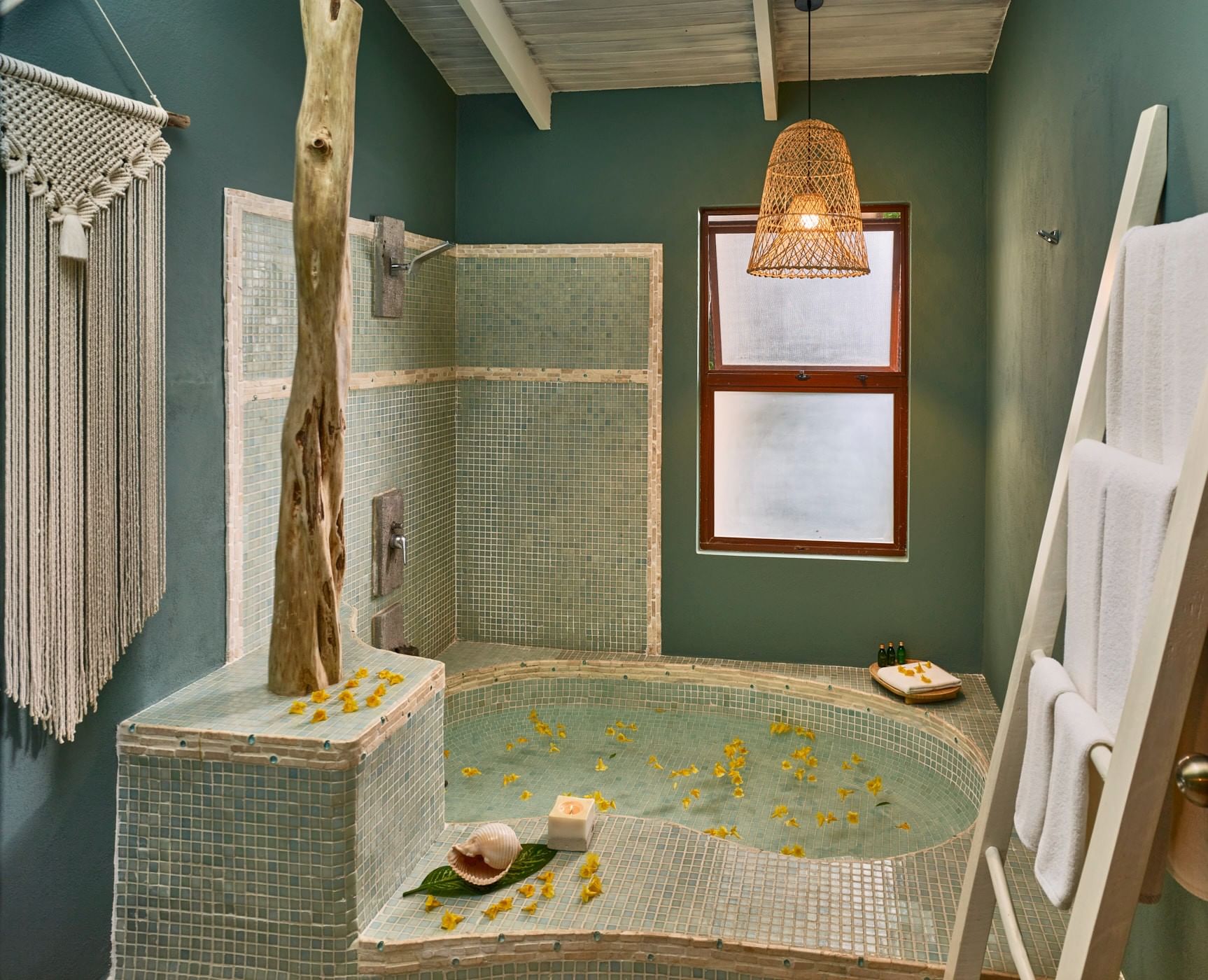 Luxury spa featuring a mosaic tub with yellow flowers and a rustic wooden pillar at Cala Luna Boutique Hotel