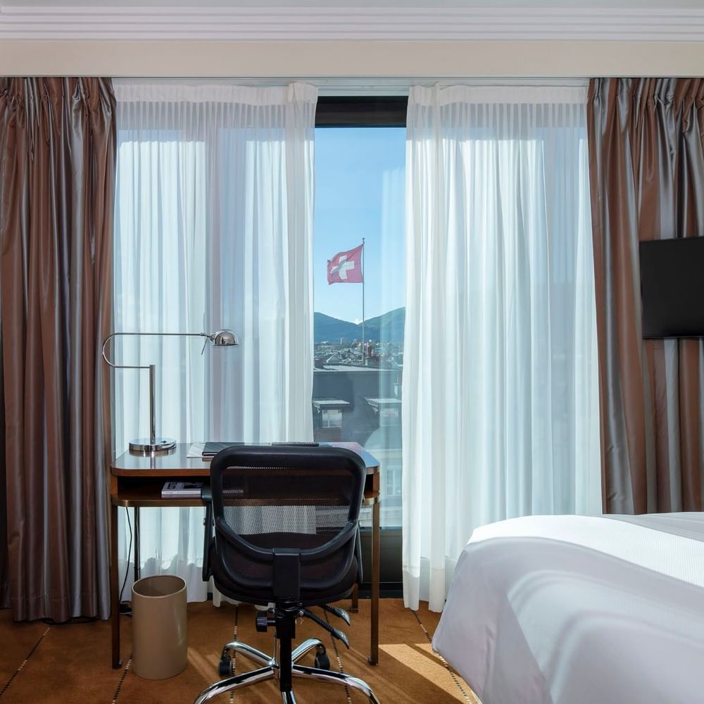Classic Single Room featuring a wooden desk by a window and a large bed at Warwick Geneva