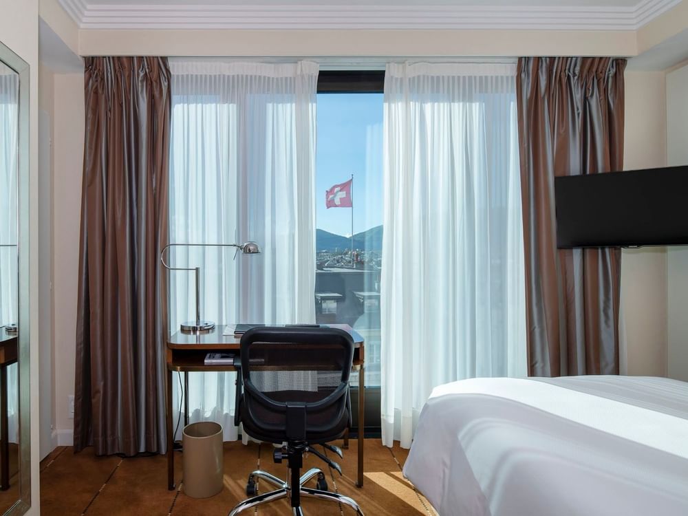 Classic Single Room featuring a wooden desk by a window and a large bed at Warwick Geneva