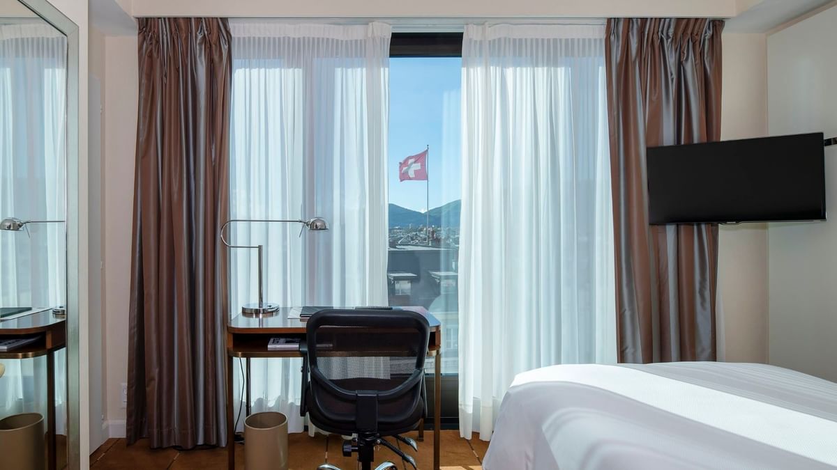 Classic Single Room featuring a wooden desk by a window and a large bed at Warwick Geneva