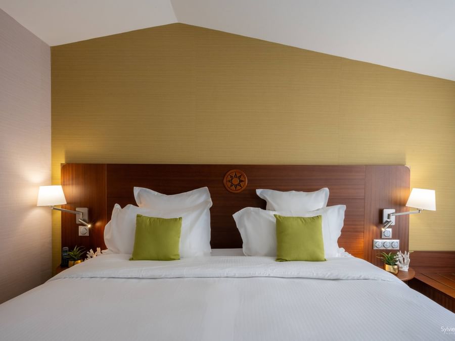 Chambre confortable avec lit blanc et oreillers verts à l'Hôtel Le Yachtman.