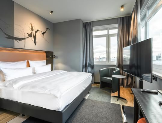 Large bed with TV and window in Superior Room at Titanic Comfort Kurfürstendamm