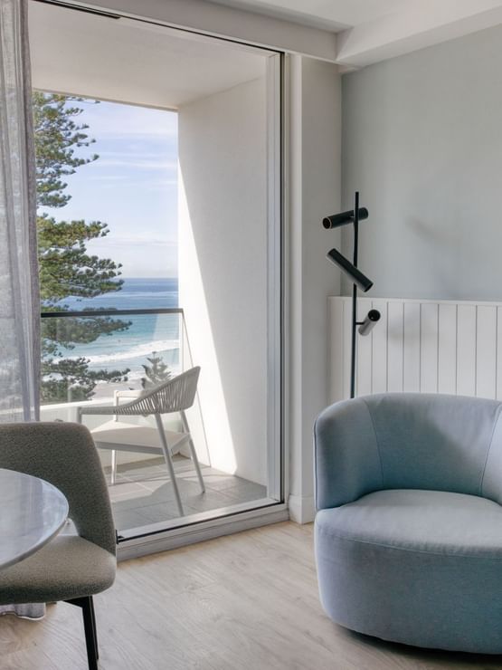Sunset View King at Elysium Manly with a marble table by a grey chair under a bowl, offering cozy Manly accommodation