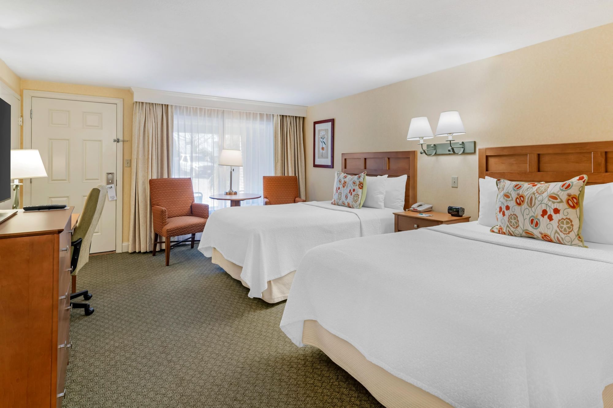 A hotel room with two double beds, a desk, and a window