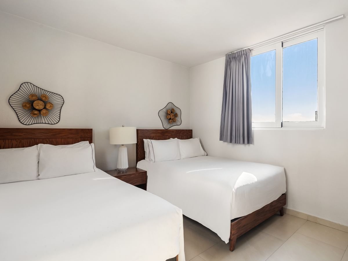 Junior Garden room featuring two beds with wooden headboards and unique floral wall art at Sunvivia Mazatlán