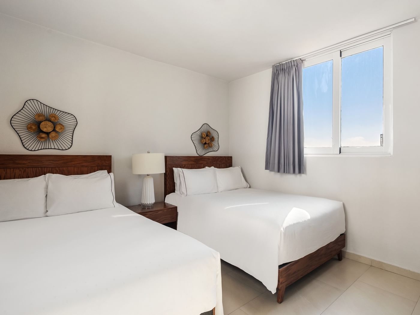 Junior Garden room featuring two beds with wooden headboards and unique floral wall art at Sunvivia Mazatlán