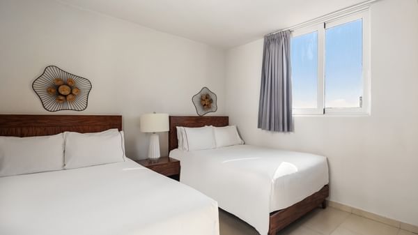 Junior Garden room featuring two beds with wooden headboards and unique floral wall art at Sunvivia Mazatlán