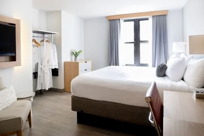 King bed by a wooden dresser and open wardrobe, facing a wall-mounted TV in Superior King room at Hotel Saint Clair