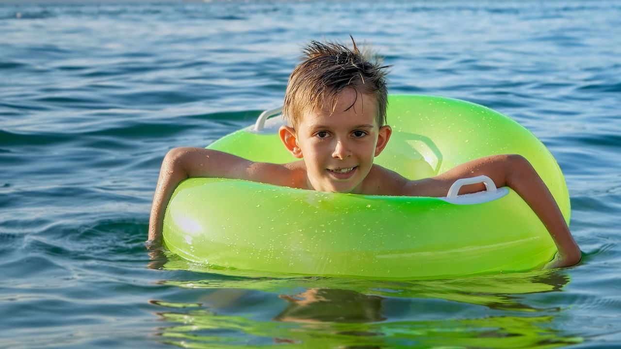 Kid relaxing in a green float on the water
