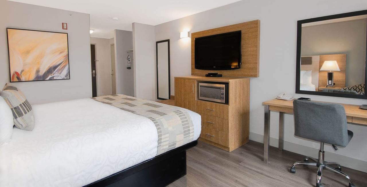 Hotel room with king bed, TV, microwave, mirror, chair and table