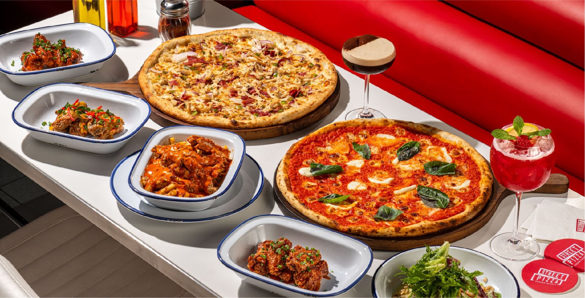 Table full of pizzas, wings, salads, and cocktails served in Gordon Ramsay Street Pizza at Sunway Resort